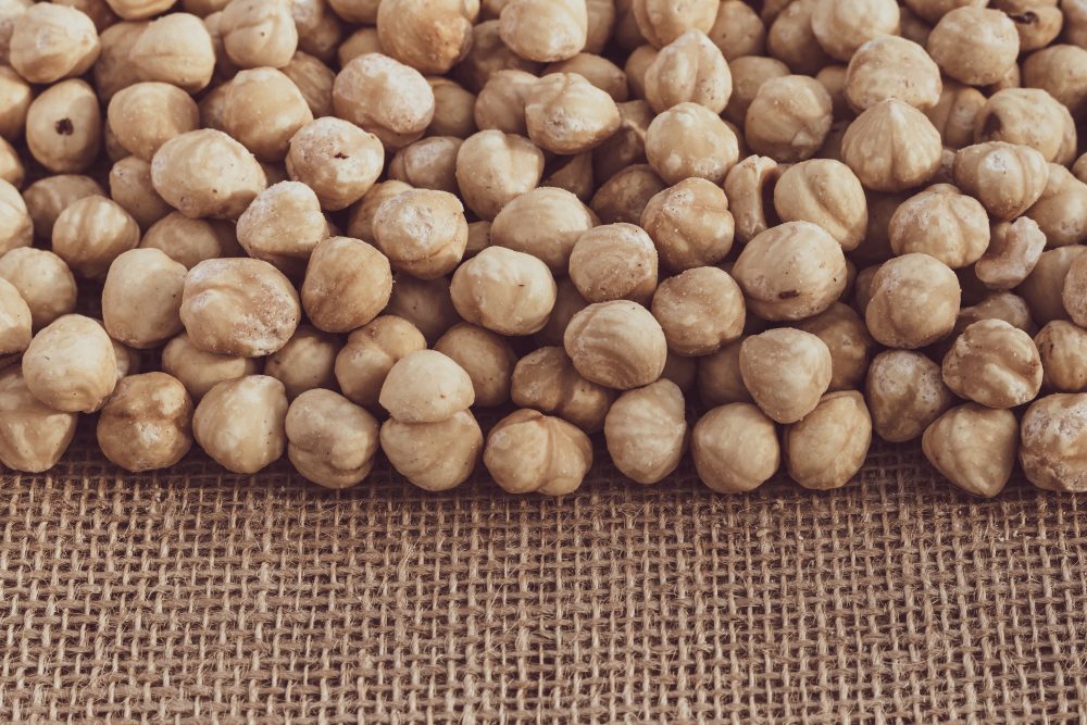 Nefkim Roasted hazelnuts on a background of burlap. Scattered Heap of nut kernels. Copy space for text. Close-up.